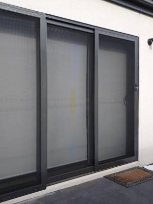 CB: 57 Angle View Stacker Sliding Security Doors Fitted With Stainless Steel Mesh. Displaying The Two Security Doors In A Closed Position & The Third Security Fixed Panel Fitted With Tamper Proof Screws In Monument.